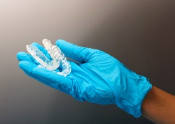 A gloved hand holding two custom-made nightguards for patients suffering from bruxism
