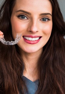 A woman holding an Invisalign aligner in Cabana Colony