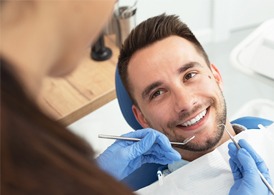 A male patient lying back in a dentist’s chair in preparation to have his teeth cleaned