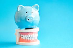 A pink piggy bank set next to a model jaw