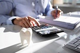 Person at a desk typing on a calculator while filling out paperwork