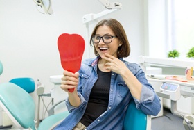woman sitting in dental chair looking in mirror smiling