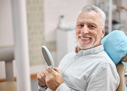 Senior patient smiling after successful dental implant salvage