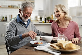 An older man and woman sitting at a table in their kitchen enjoying a meal together