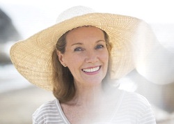 An older woman wearing a wide-brimmed hat and feeling confident in her smile in Juno Beach