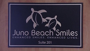 Wall plaque that reads Juno Beach Smiles Enhanced Smiles Enhanced Lives Suite 201