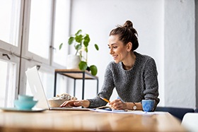 Woman smiling while working on laptop at home