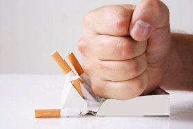 Person’s fist smashing a pack of cigarettes