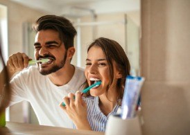 A couple brushing their teeth together.