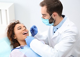 A male dentist examines a female patient’s oral cavity during a general checkup