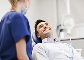 A male patient smiles at his dentist as she prepares to perform an oral cancer screening