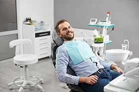 Happy male dental patient relaxing in exam chair
