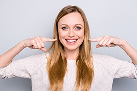 young woman pointing to smile 