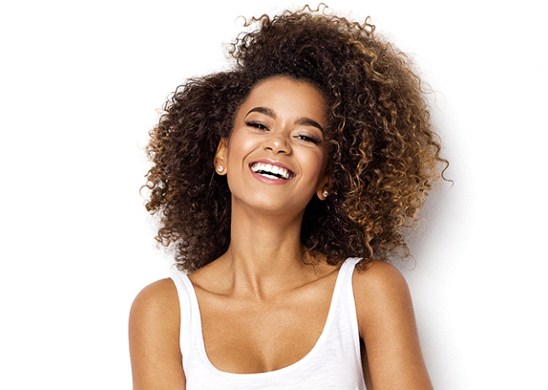 A young woman wearing a white tank top and smiling after receiving veneers near Palm Beach Gardens