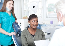 A woman seated in the dentist’s chair listening to her cosmetic dentist discuss the process of veneer placement