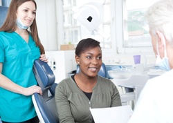 A woman seated in the dentist’s chair listening to her cosmetic dentist discuss the process of veneer placement
