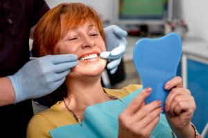 An older woman examines her teeth.