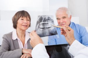 A dentist showing an older couple an X-ray.