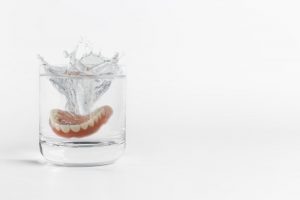 dentures being placed in a glass of water