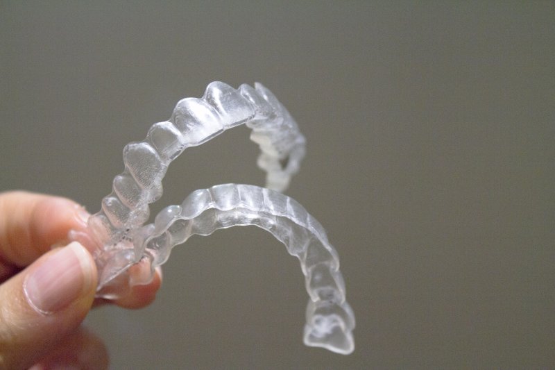 a person holding a set of clear Invisalign aligners