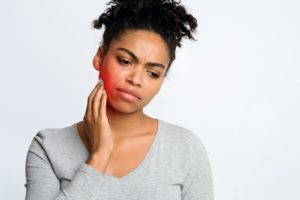 frowning woman with toothache, in need of emergency dentist