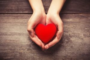 Outstretched hands holding heart for American Heart Health Month