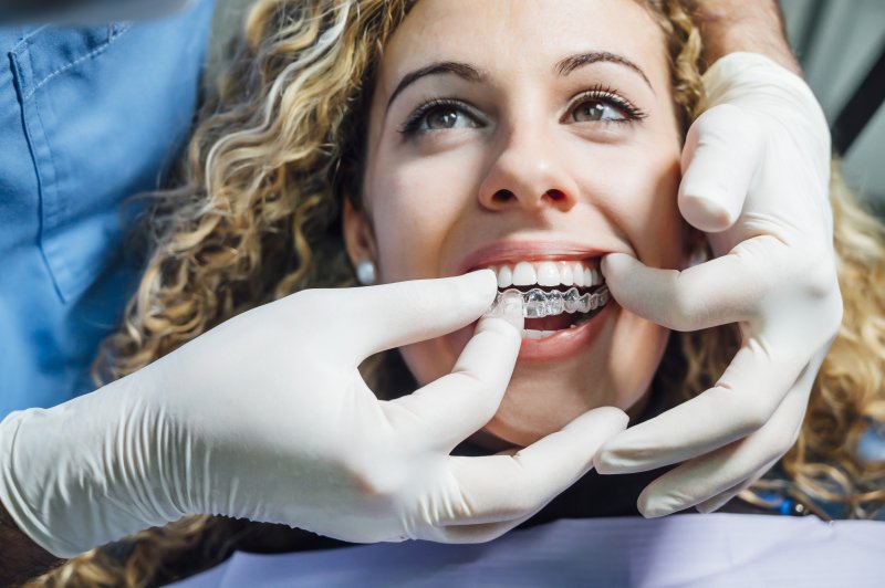 Dentist placing Invisalign trays in patient's mouth