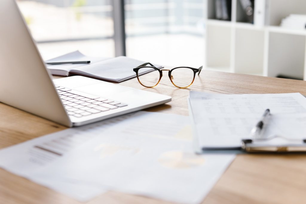 Work desk with glasses, paperwork, and computer