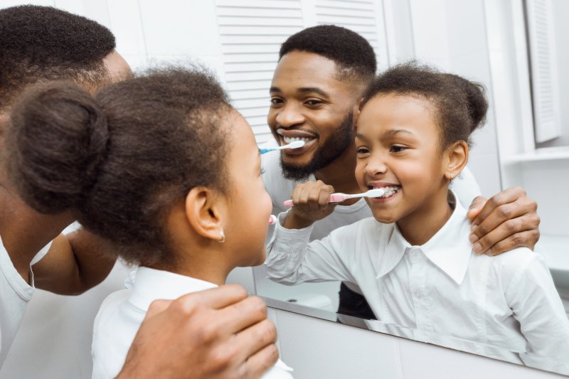 father and daughter brushing teeth