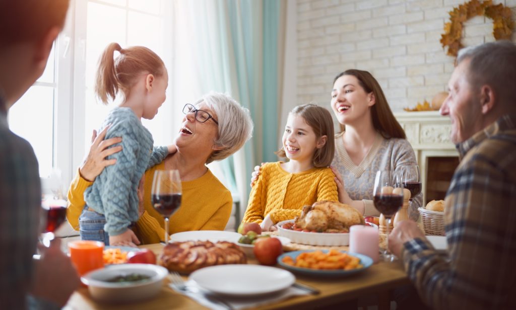 Family smiling while enjoying Thanksgiving meal together