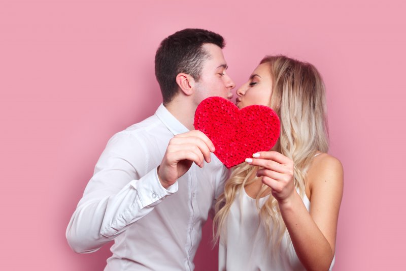 young couple holding heart and kissing