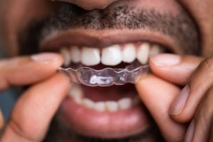 a woman smiling and holding her clear aligner