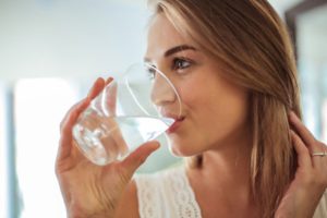 a closeup of someone drinking a glass of water