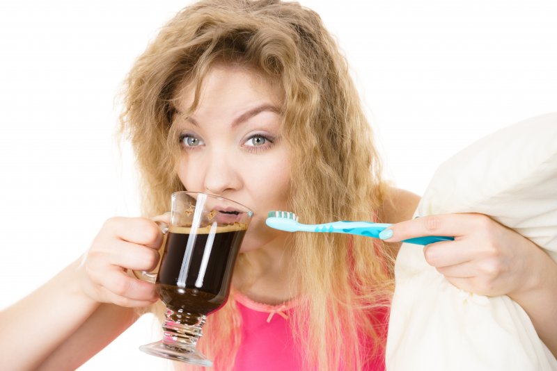 A woman drinking a glass of tea before she brushes her teeth