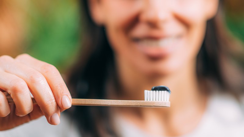 woman using activated charcoal to clean her teeth