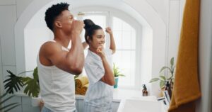 Young man and woman floss and brush their teeth. 
